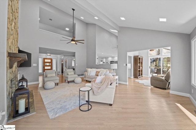 living room with ceiling fan, a high ceiling, and light hardwood / wood-style flooring