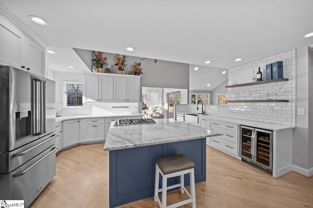 kitchen featuring white cabinetry, a breakfast bar area, appliances with stainless steel finishes, tasteful backsplash, and wine cooler