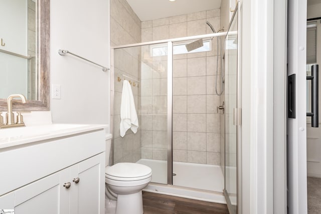 bathroom with hardwood / wood-style flooring, toilet, walk in shower, and vanity