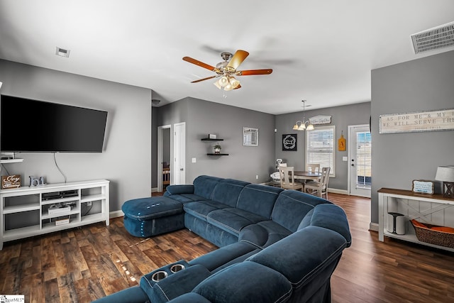 living room with ceiling fan with notable chandelier and dark hardwood / wood-style floors