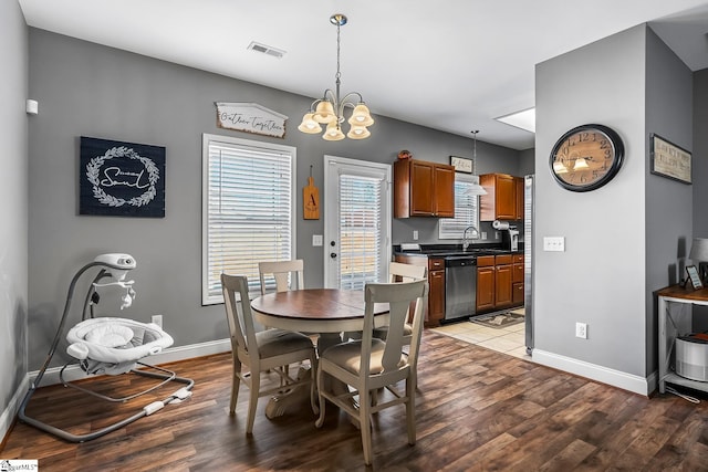 dining space with sink, hardwood / wood-style floors, and a chandelier