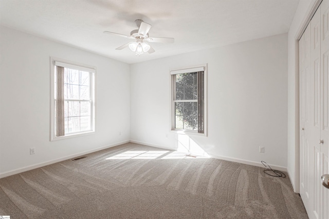 unfurnished bedroom featuring ceiling fan, light colored carpet, and a closet