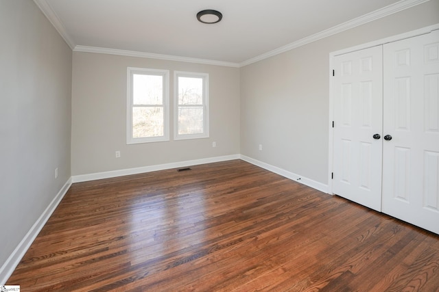 unfurnished bedroom featuring a closet, dark hardwood / wood-style flooring, and crown molding