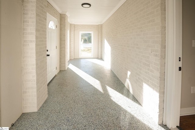 hall featuring brick wall and ornamental molding