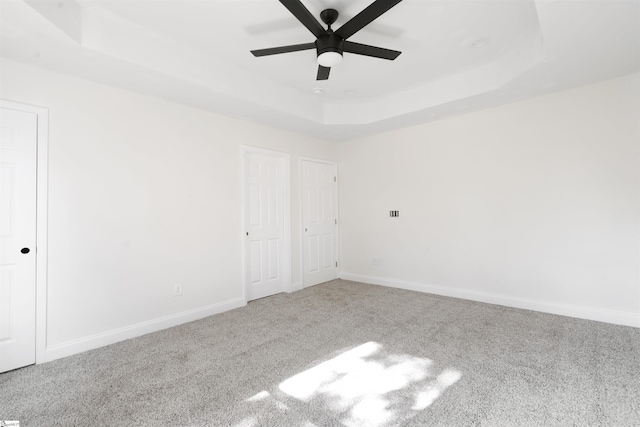 empty room featuring ceiling fan, carpet, and a raised ceiling