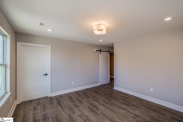 empty room with a barn door and dark hardwood / wood-style floors