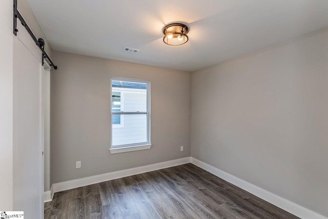 empty room featuring dark wood-type flooring and a barn door