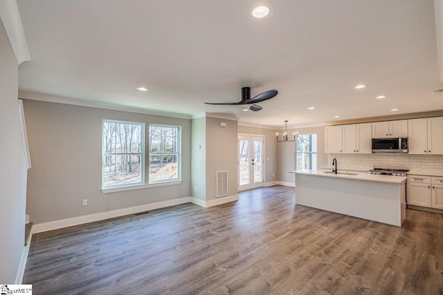 kitchen featuring pendant lighting, a wealth of natural light, crown molding, white cabinets, and french doors