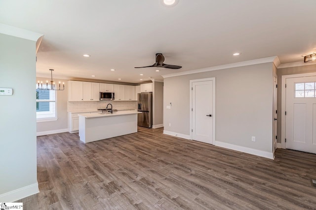 kitchen with ceiling fan with notable chandelier, white cabinetry, stainless steel appliances, hanging light fixtures, and a center island with sink