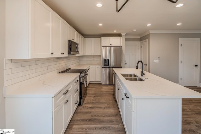 kitchen with light stone countertops, white cabinetry, stainless steel appliances, sink, and a center island with sink