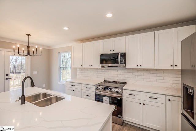 kitchen featuring decorative light fixtures, appliances with stainless steel finishes, sink, and light stone counters