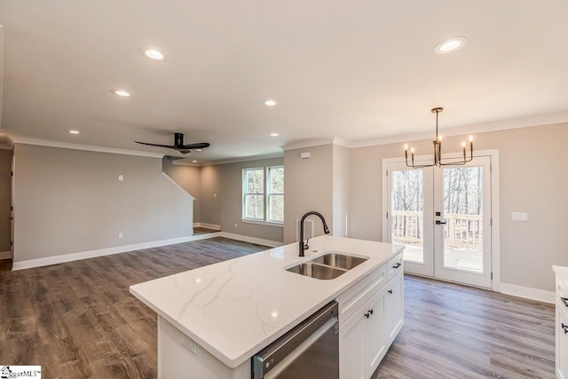 kitchen with white cabinetry, a center island with sink, hanging light fixtures, stainless steel dishwasher, and sink