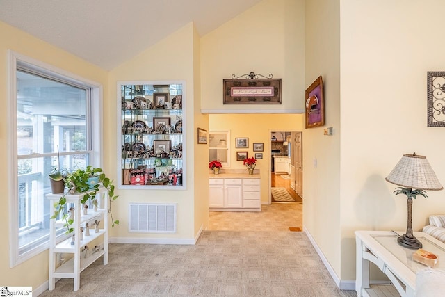 hallway featuring light carpet and lofted ceiling