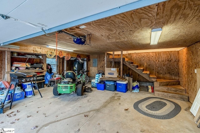 garage with a garage door opener, electric panel, and wood walls