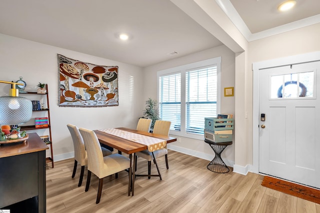 dining room with ornamental molding and light hardwood / wood-style flooring