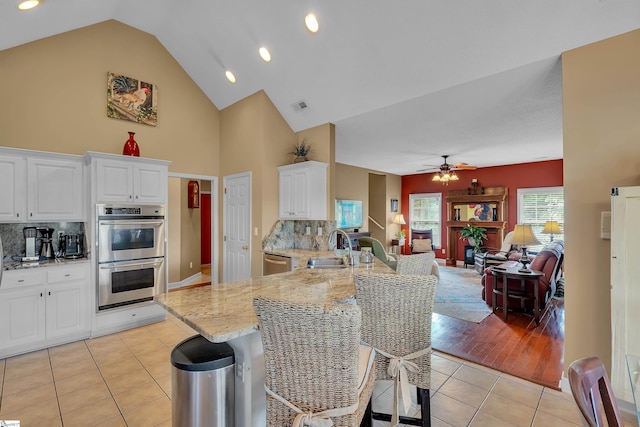 kitchen featuring white cabinets, decorative backsplash, appliances with stainless steel finishes, and light tile patterned floors