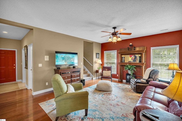 living room featuring a textured ceiling, ceiling fan, and hardwood / wood-style floors