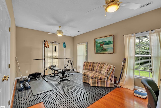 exercise area featuring ceiling fan, hardwood / wood-style floors, and a textured ceiling