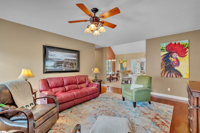 living room featuring lofted ceiling, ceiling fan with notable chandelier, and hardwood / wood-style floors