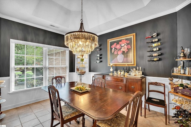 tiled dining room featuring a tray ceiling, crown molding, and a notable chandelier