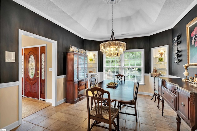 dining room with a textured ceiling, ornamental molding, a raised ceiling, a chandelier, and light tile patterned floors