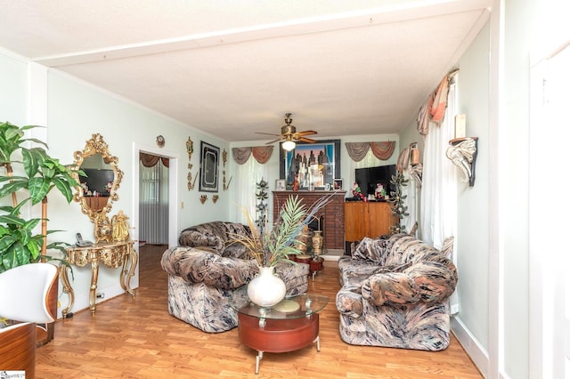 living room with ceiling fan, ornamental molding, a fireplace, and hardwood / wood-style floors