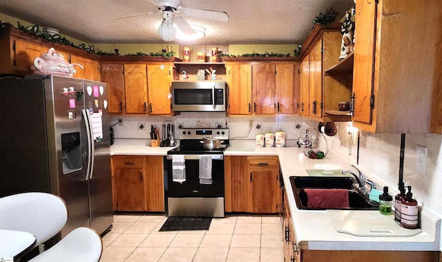 kitchen featuring a textured ceiling, stainless steel appliances, decorative backsplash, sink, and light tile patterned flooring