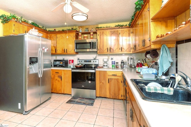 kitchen with ceiling fan, light tile patterned floors, appliances with stainless steel finishes, and a textured ceiling