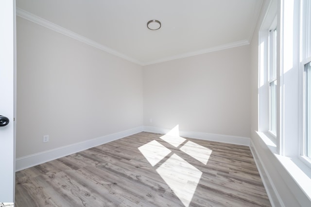 empty room featuring crown molding, light wood finished floors, and baseboards