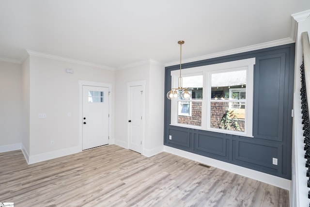 entrance foyer featuring ornamental molding, light wood-style floors, and baseboards