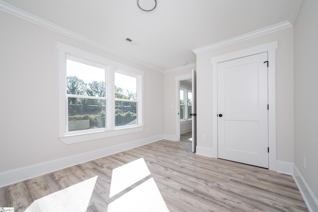 unfurnished bedroom with baseboards, light wood-type flooring, visible vents, and crown molding