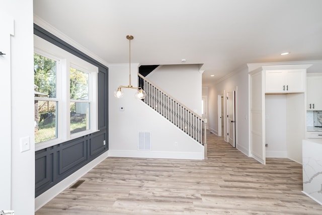 foyer featuring light wood-type flooring and ornamental molding