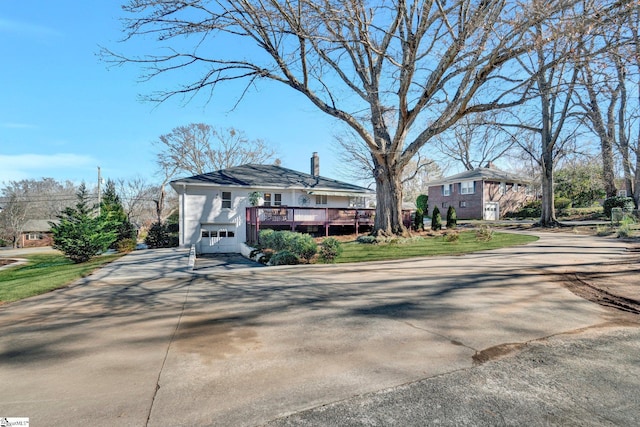 view of front of property with a garage, a deck, and a front lawn