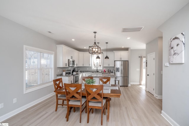 dining space with sink and light wood-type flooring