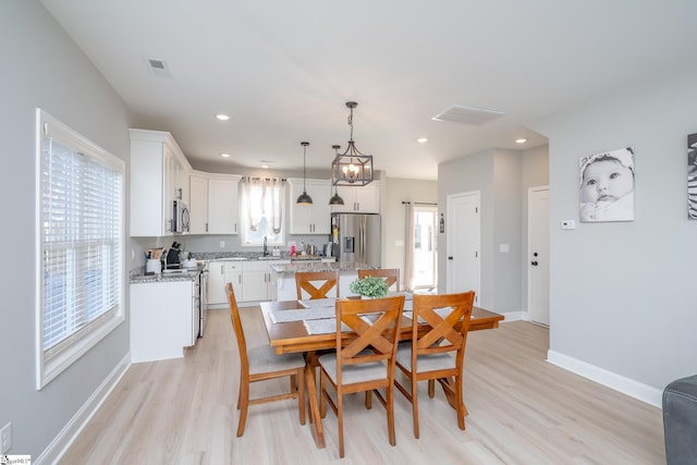 dining area with a chandelier, light hardwood / wood-style flooring, and sink