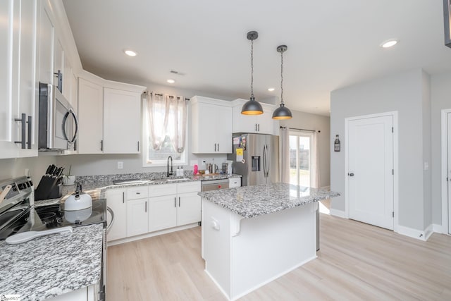 kitchen featuring pendant lighting, a kitchen island, sink, appliances with stainless steel finishes, and white cabinets