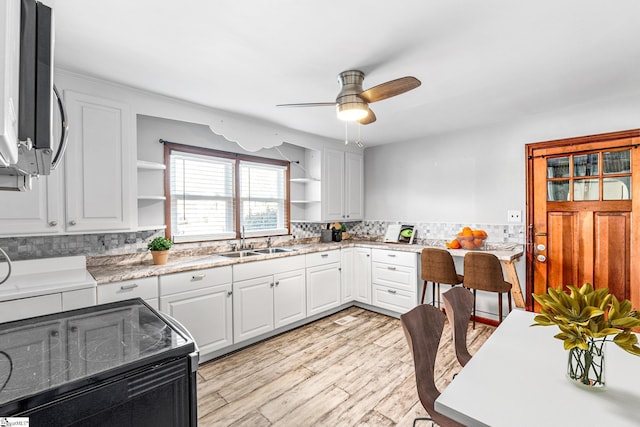 kitchen with white cabinetry, black / electric stove, sink, ceiling fan, and light hardwood / wood-style flooring