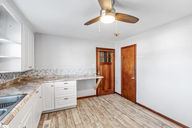 kitchen featuring white cabinets, built in desk, sink, ceiling fan, and light hardwood / wood-style flooring