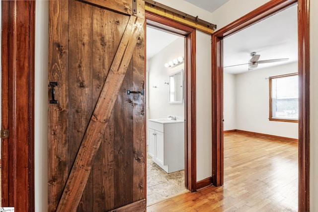 corridor featuring sink, a barn door, and light wood-type flooring