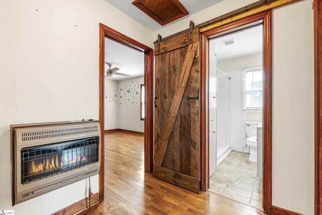 hall featuring heating unit, a barn door, and light hardwood / wood-style floors