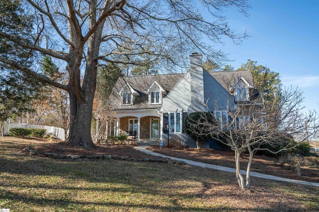 cape cod home with covered porch and a front lawn