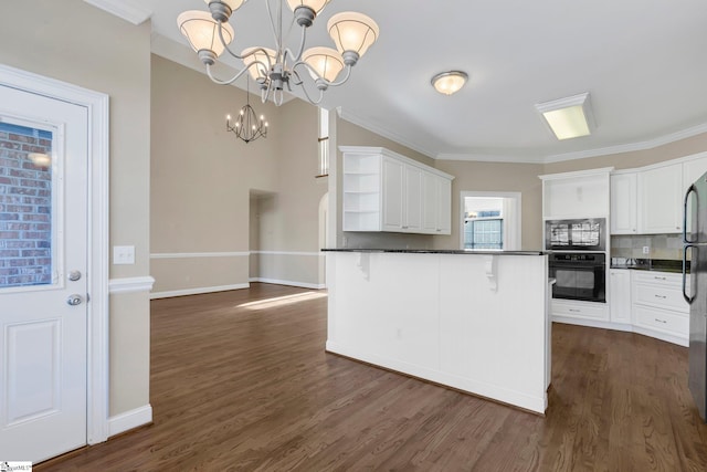 kitchen with a kitchen breakfast bar, pendant lighting, white cabinets, and oven