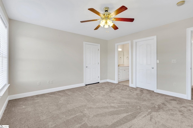 unfurnished bedroom featuring light carpet, ceiling fan, connected bathroom, and multiple windows