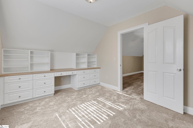 additional living space with built in desk, vaulted ceiling, and light carpet