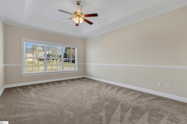 carpeted spare room with ceiling fan, crown molding, and a tray ceiling