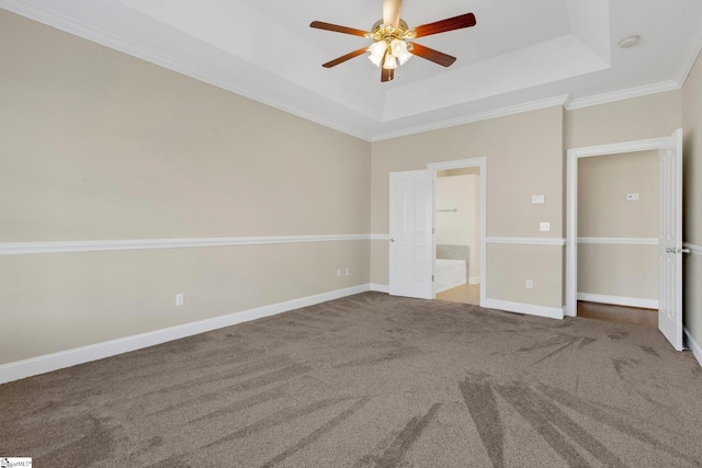 unfurnished bedroom featuring ensuite bath, a raised ceiling, carpet flooring, ceiling fan, and crown molding