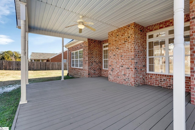 wooden terrace featuring ceiling fan and a lawn