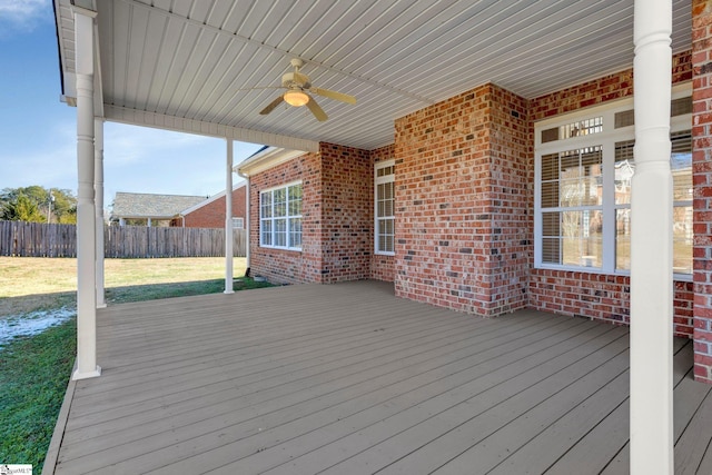 wooden terrace featuring ceiling fan and a lawn