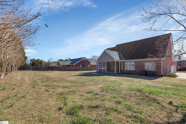 rear view of house with central AC unit and a yard