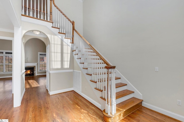 staircase with ornamental molding and hardwood / wood-style flooring